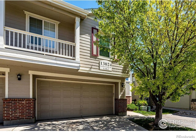 13024 Grant Cir W Unit A, Thornton, CO 80241 - view of front of property with brick siding, an attached garage, concrete driveway, and a balcony