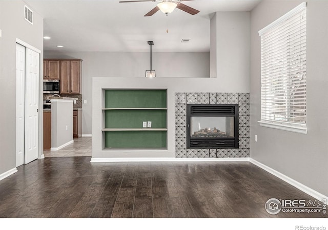 13024 Grant Cir W Unit A, Thornton, CO 80241 - unfurnished living room with ceiling fan, baseboards, dark wood-type flooring, a tiled fireplace, and recessed lighting