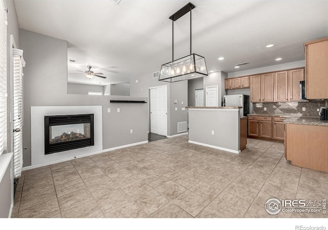 13024 Grant Cir W Unit A, Thornton, CO 80241 - kitchen featuring freestanding refrigerator, a ceiling fan, backsplash, a multi sided fireplace, and hanging light fixtures