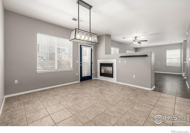 13024 Grant Cir W Unit A, Thornton, CO 80241 - unfurnished living room with healthy amount of natural light, ceiling fan, a glass covered fireplace, and baseboards