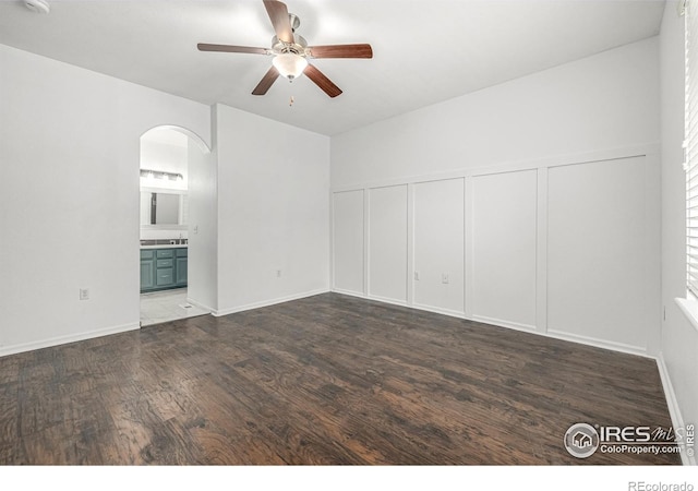 13024 Grant Cir W Unit A, Thornton, CO 80241 - empty room featuring a ceiling fan, arched walkways, wood finished floors, and a decorative wall
