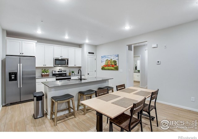 2086 Autumn Moon Dr Unit 7, Windsor, CO 80550 - kitchen with appliances with stainless steel finishes, a sink, light wood-style flooring, a center island with sink, and tasteful backsplash