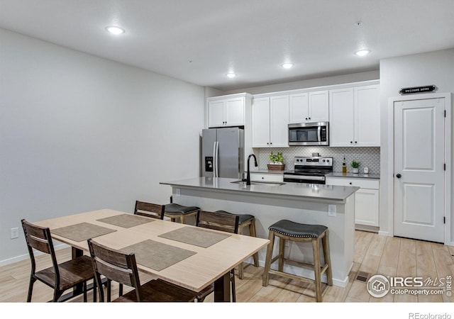 2086 Autumn Moon Dr Unit 7, Windsor, CO 80550 - kitchen with appliances with stainless steel finishes, a sink, an island with sink, decorative backsplash, and white cabinetry