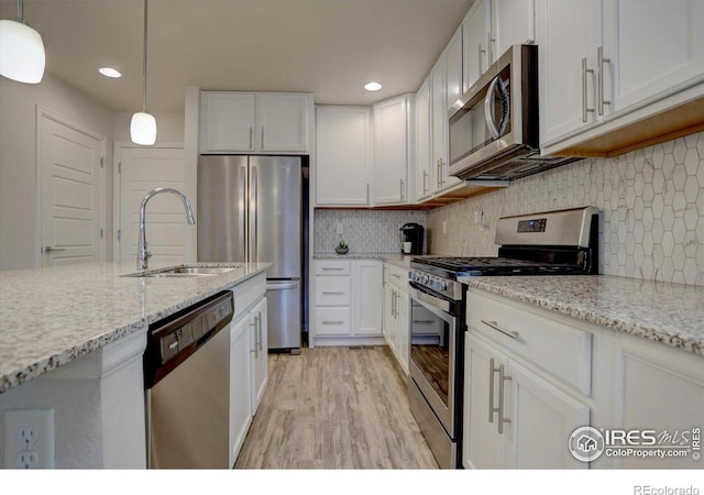 5863 Boston St, Denver, CO 80238 - kitchen with stainless steel appliances, a sink, white cabinets, light wood-type flooring, and recessed lighting