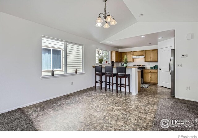 2220 Woodbury Ln, Fort Collins, CO 80524 - kitchen featuring lofted ceiling, under cabinet range hood, brown cabinetry, a peninsula, and a chandelier