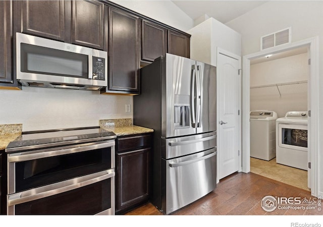 2767 Stallion Way, Mead, CO 80542 - kitchen with appliances with stainless steel finishes, washing machine and clothes dryer, dark brown cabinets, and light stone countertops