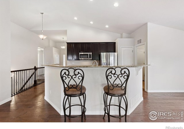 2767 Stallion Way, Mead, CO 80542 - kitchen with stainless steel appliances, dark wood finished floors, a breakfast bar, dark brown cabinets, and light stone countertops
