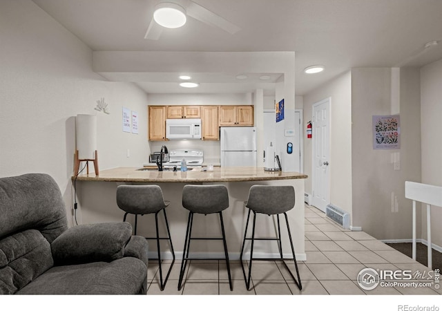 1065 University Ave Unit 121, Boulder, CO 80302 - kitchen with white appliances, a kitchen bar, a peninsula, a sink, and light brown cabinets