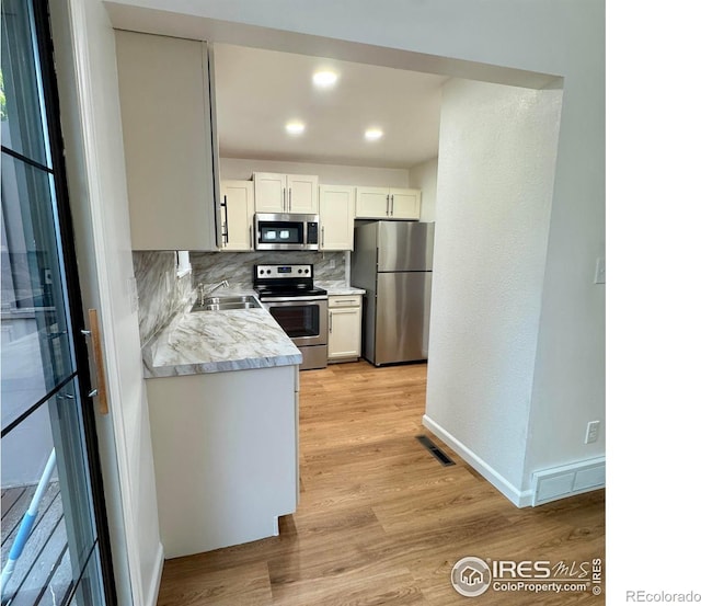 517 46th Ave, Greeley, CO 80634 - kitchen featuring stainless steel appliances, a sink, light countertops, backsplash, and light wood-style flooring