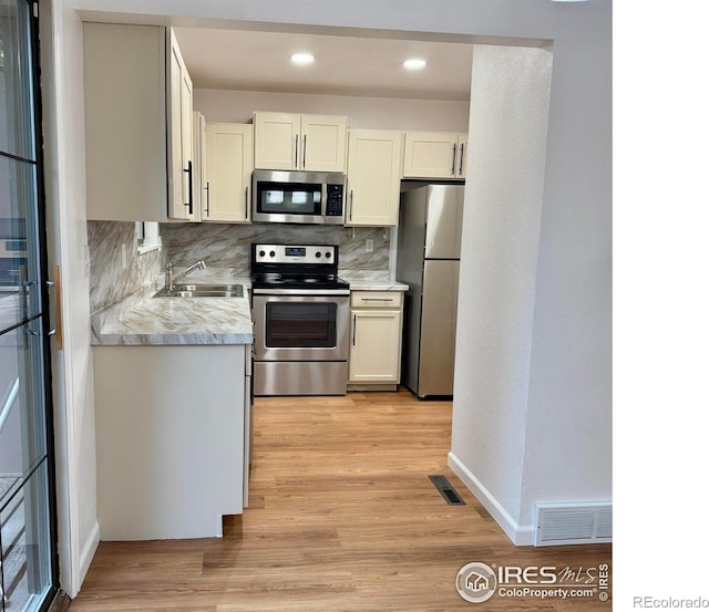 517 46th Ave, Greeley, CO 80634 - kitchen featuring appliances with stainless steel finishes, a sink, backsplash, light wood finished floors, and baseboards