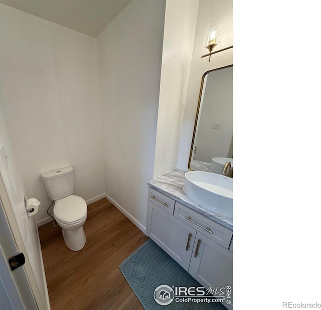 517 46th Ave, Greeley, CO 80634 - half bathroom with wood finished floors, toilet, vanity, and baseboards