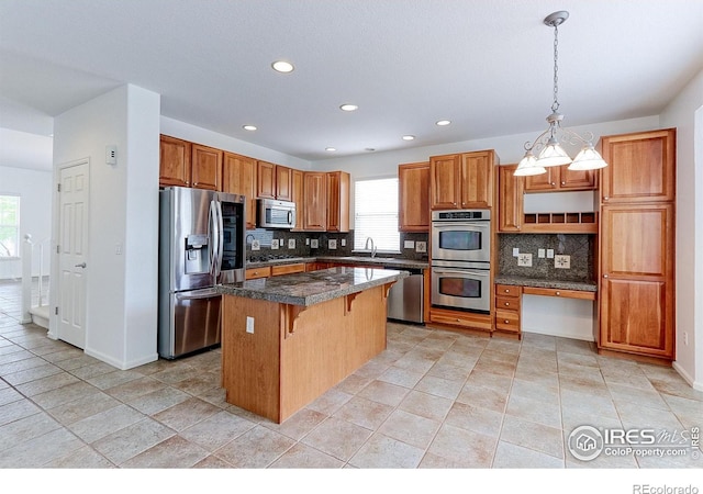 2631 E 136th Pl, Thornton, CO 80602 - kitchen with appliances with stainless steel finishes, a kitchen island, backsplash, healthy amount of natural light, and recessed lighting