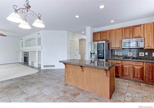 2631 E 136th Pl, Thornton, CO 80602 - kitchen featuring stainless steel appliances, a breakfast bar, a kitchen island, a fireplace with flush hearth, and tasteful backsplash