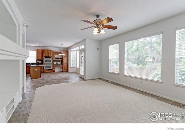 2631 E 136th Pl, Thornton, CO 80602 - unfurnished living room with healthy amount of natural light, light tile patterned floors, ceiling fan, and baseboards