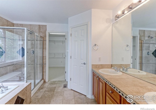 2631 E 136th Pl, Thornton, CO 80602 - bathroom featuring a stall shower, a garden tub, double vanity, a walk in closet, and tile patterned flooring