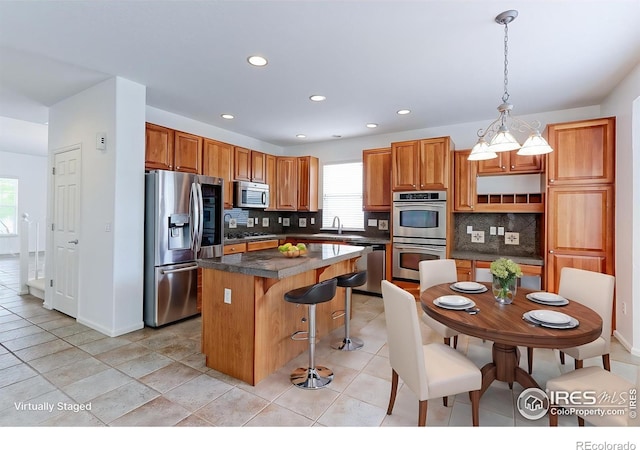 2631 E 136th Pl, Thornton, CO 80602 - kitchen with stainless steel appliances, a kitchen island, tasteful backsplash, dark countertops, and recessed lighting