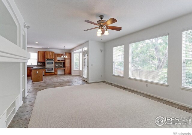 2631 E 136th Pl, Thornton, CO 80602 - unfurnished living room with healthy amount of natural light, light tile patterned floors, and a ceiling fan