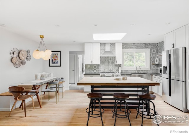 3445 Martin Dr, Boulder, CO 80305 - kitchen with stainless steel fridge with ice dispenser, wall chimney range hood, a skylight, and decorative backsplash