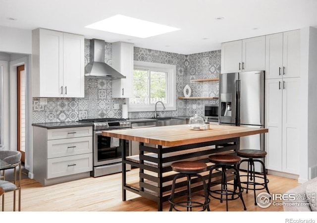 3445 Martin Dr, Boulder, CO 80305 - kitchen featuring stainless steel appliances, wall chimney exhaust hood, a skylight, decorative backsplash, and light wood-style flooring