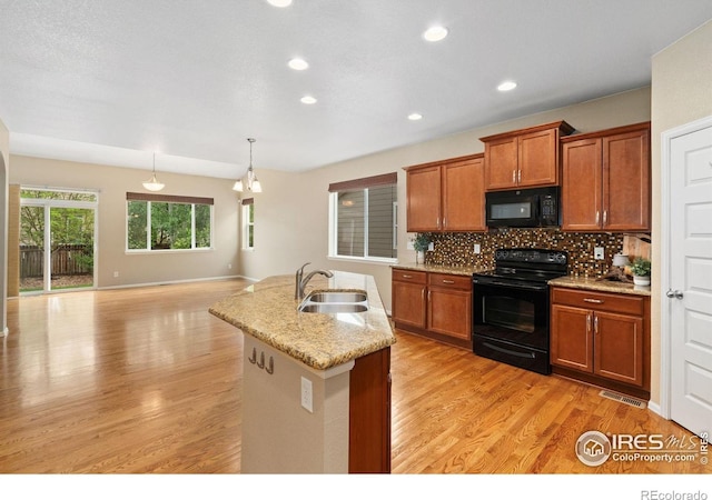 6340 Spring Valley Rd, Timnath, CO 80547 - kitchen featuring black appliances, a sink, brown cabinetry, light wood-style flooring, and decorative backsplash