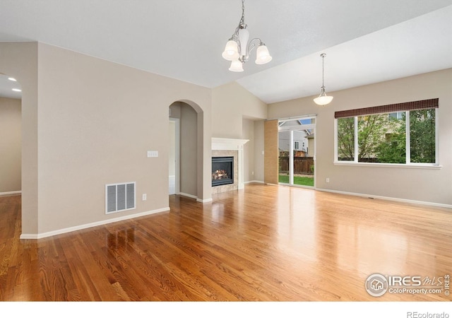 6340 Spring Valley Rd, Timnath, CO 80547 - unfurnished living room with vaulted ceiling, wood finished floors, arched walkways, baseboards, and a chandelier
