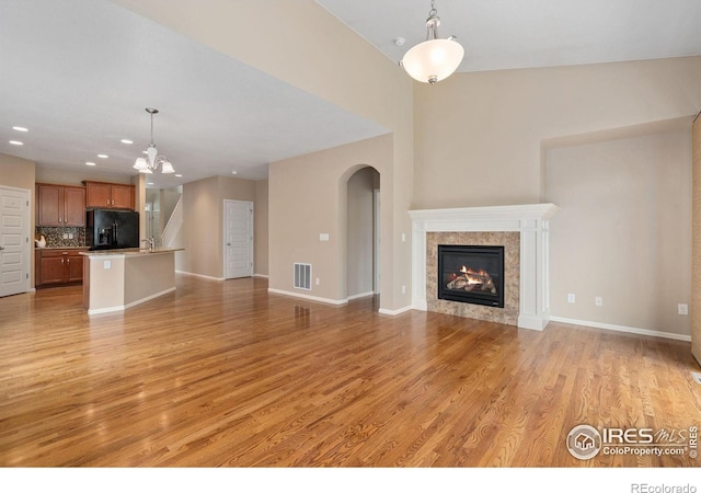 6340 Spring Valley Rd, Timnath, CO 80547 - unfurnished living room with light wood-style floors, recessed lighting, a chandelier, a fireplace, and arched walkways