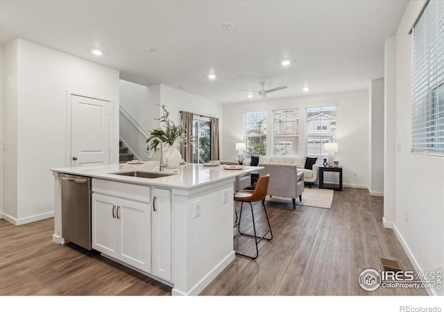 645 Flintwood Pl, Lafayette, CO 80026 - kitchen featuring stainless steel dishwasher, a sink, wood finished floors, an island with sink, and recessed lighting