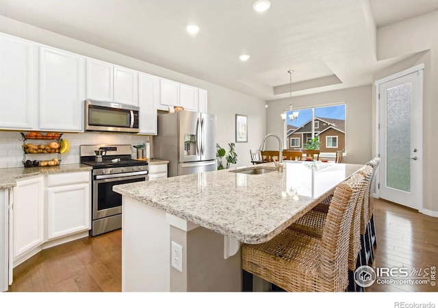 8255 Eagle Dr, Greeley, CO 80634 - kitchen featuring stainless steel appliances, a sink, wood-type flooring, white cabinets, and recessed lighting