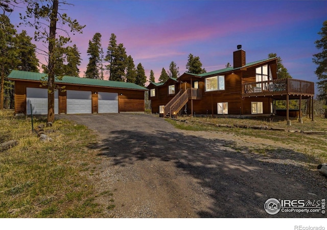 1954 Bluestem Way, Fairplay, CO 80440 - view of front of home featuring an outbuilding, a chimney, a deck, a detached garage, and asphalt driveway