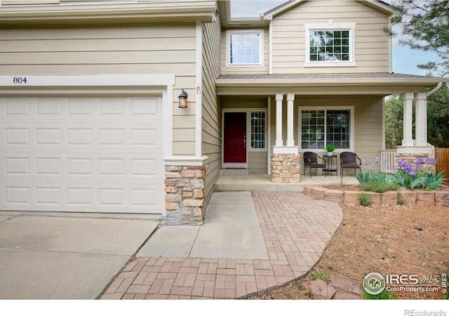 804 Nelson Park Ln, Longmont, CO 80503 - view of exterior entry with a porch, concrete driveway, stone siding, and an attached garage