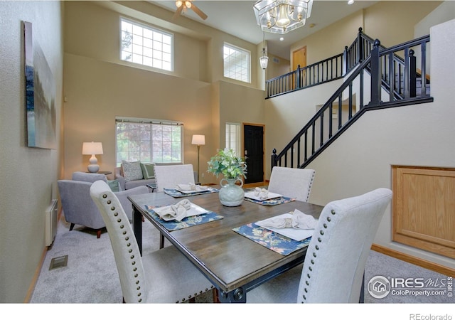 804 Nelson Park Ln, Longmont, CO 80503 - carpeted dining area featuring a chandelier, a towering ceiling, stairs, ceiling fan, and radiator