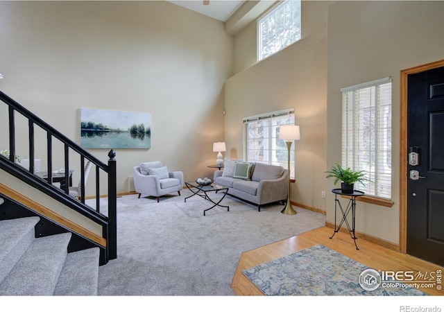 804 Nelson Park Ln, Longmont, CO 80503 - carpeted living room with stairway, baseboards, a towering ceiling, and wood finished floors