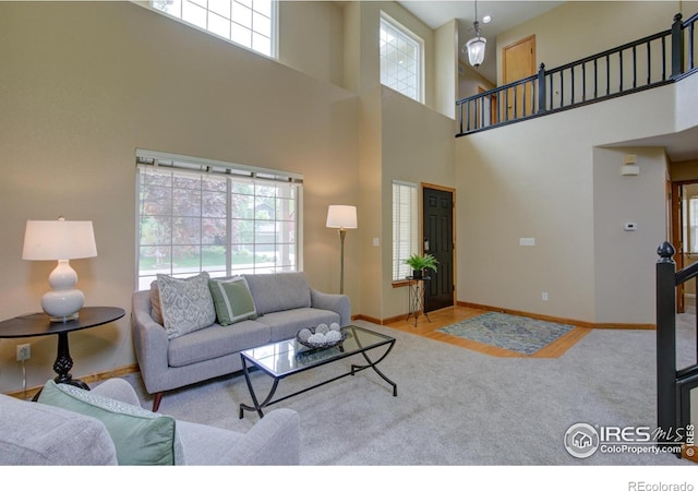 804 Nelson Park Ln, Longmont, CO 80503 - carpeted living area with healthy amount of natural light, baseboards, a towering ceiling, and stairs