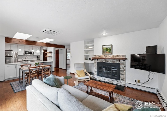 3255 34th St Unit 42, Boulder, CO 80301 - living area featuring a fireplace, wood finished floors, a skylight, and a baseboard heating unit