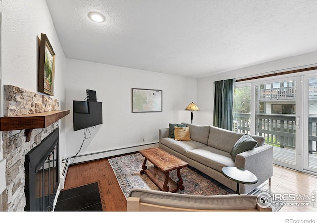 3255 34th St Unit 42, Boulder, CO 80301 - living area featuring a textured ceiling, wood finished floors, a glass covered fireplace, and a baseboard heating unit