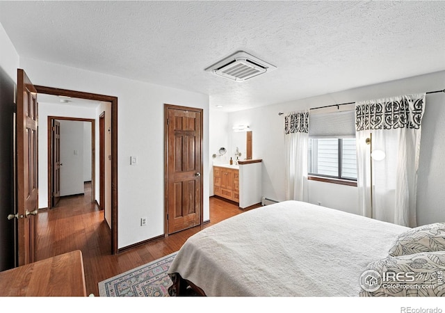 3255 34th St Unit 42, Boulder, CO 80301 - bedroom featuring wood finished floors, a baseboard radiator, connected bathroom, and a textured ceiling