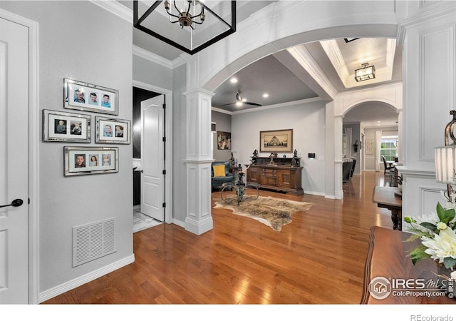 2038 Vineyard Dr, Windsor, CO 80550 - foyer entrance featuring arched walkways, ornate columns, wood finished floors, ornamental molding, and baseboards