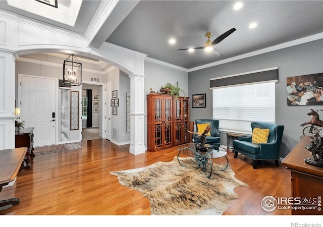 2038 Vineyard Dr, Windsor, CO 80550 - living area featuring arched walkways, ornate columns, light wood-style floors, a ceiling fan, and ornamental molding