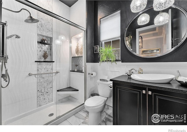 2038 Vineyard Dr, Windsor, CO 80550 - full bathroom featuring a stall shower, toilet, vanity, marble look tiles, and a wainscoted wall