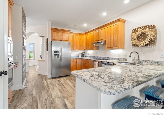 36091 Appy Rd, Eaton, CO 80615 - kitchen featuring appliances with stainless steel finishes, a sink, a peninsula, under cabinet range hood, and light stone counters