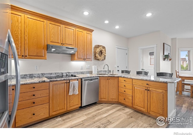 36091 Appy Rd, Eaton, CO 80615 - kitchen featuring appliances with stainless steel finishes, a peninsula, under cabinet range hood, a sink, and light wood-style flooring