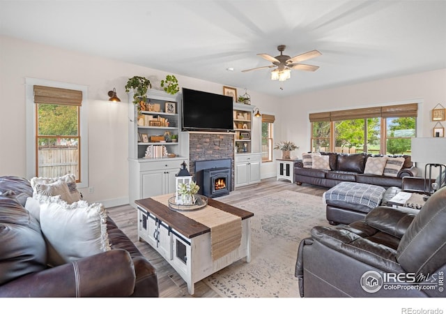 36091 Appy Rd, Eaton, CO 80615 - living area featuring plenty of natural light, a ceiling fan, a stone fireplace, and light wood-style floors