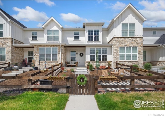 1922 Naturita St, Loveland, CO 80538 - view of front of property with stone siding, board and batten siding, a fenced front yard, and a gate
