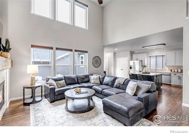 5111 Mt St Vrain Ave, Frederick, CO 80504 - living room with dark wood-type flooring, a high ceiling, a glass covered fireplace, and baseboards