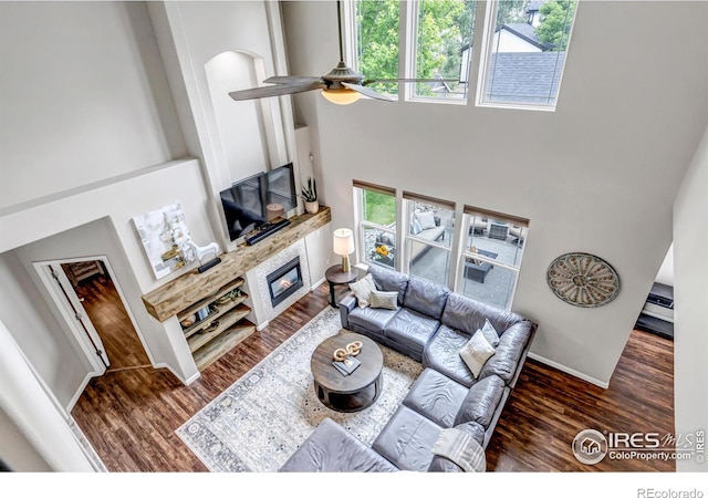 5111 Mt St Vrain Ave, Frederick, CO 80504 - living area featuring a towering ceiling, a large fireplace, wood finished floors, a ceiling fan, and baseboards