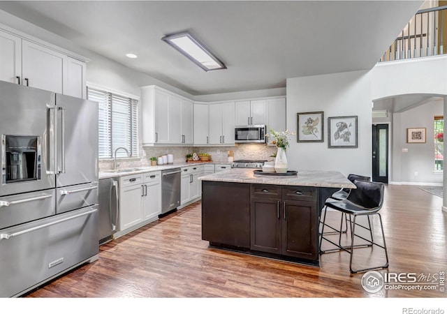 5111 Mt St Vrain Ave, Frederick, CO 80504 - kitchen featuring appliances with stainless steel finishes, a sink, washer / clothes dryer, wood finished floors, and a center island