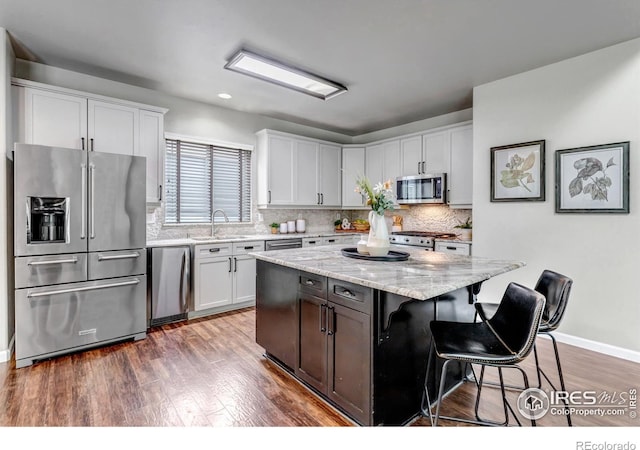 5111 Mt St Vrain Ave, Frederick, CO 80504 - kitchen with stainless steel appliances, a breakfast bar, dark wood-type flooring, tasteful backsplash, and recessed lighting