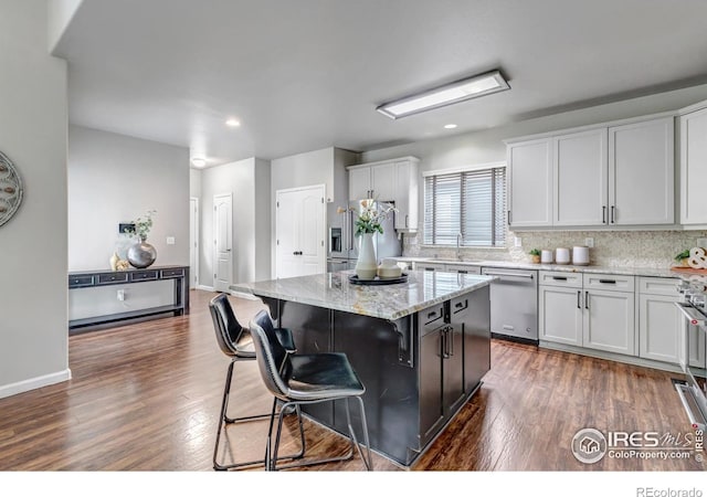 5111 Mt St Vrain Ave, Frederick, CO 80504 - kitchen with appliances with stainless steel finishes, dark wood-style floors, a kitchen bar, white cabinetry, and recessed lighting