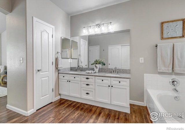 5111 Mt St Vrain Ave, Frederick, CO 80504 - bathroom featuring wood finished floors, double vanity, baseboards, and a garden tub