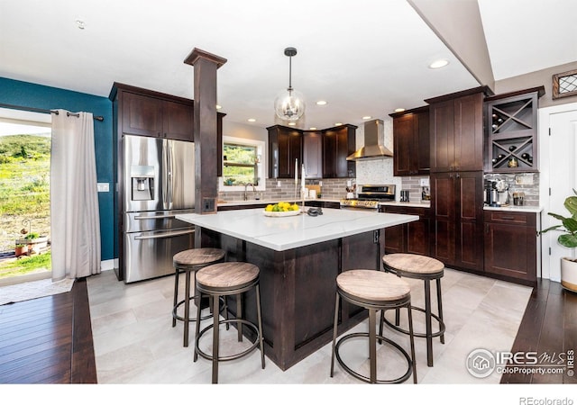 4721 Arthur Mae Ln, Laporte, CO 80535 - kitchen featuring appliances with stainless steel finishes, wall chimney exhaust hood, decorative backsplash, a kitchen island, and a kitchen breakfast bar